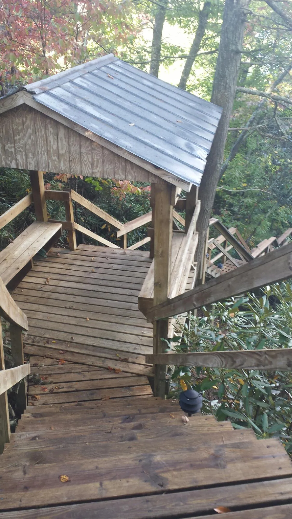 Metal roofed shelter over wooden steps on a wooded walkway — Skylight Repair & Installation work by our crew in Oak Park